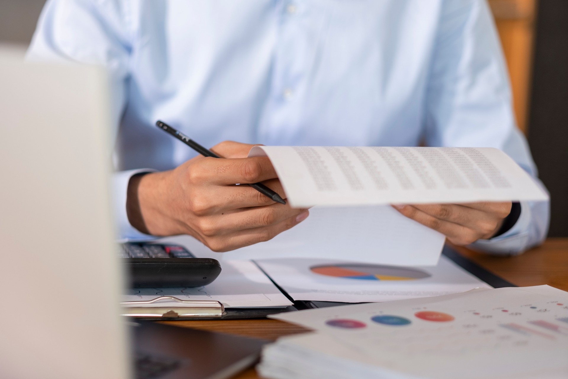 Businessman examining financial reports and analyzing charts with a pen in hand
